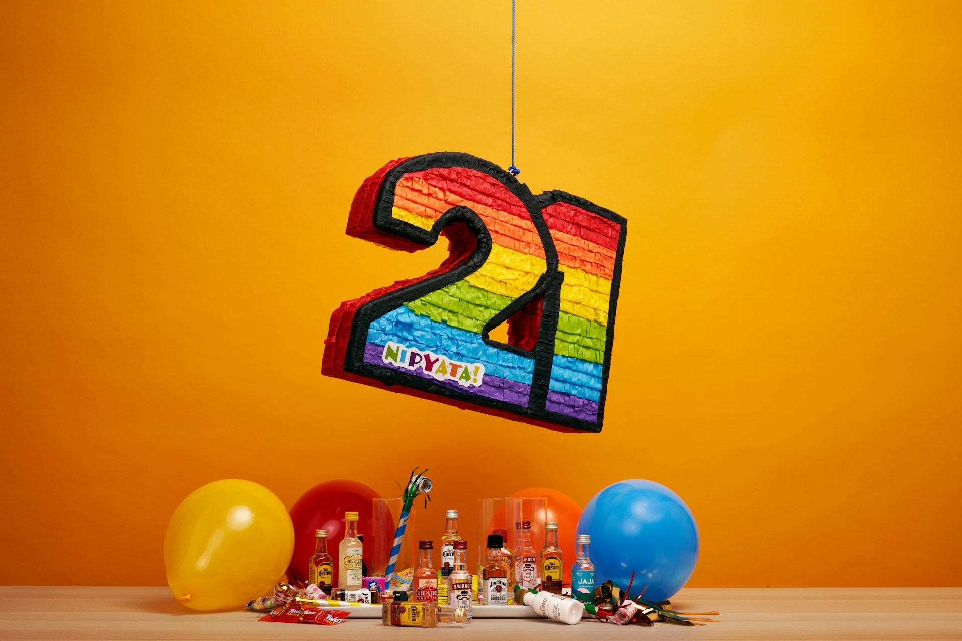 A number twenty-one, rainbow-coloured sign hanging from a string next to balloons, because WordPress is turning 21!