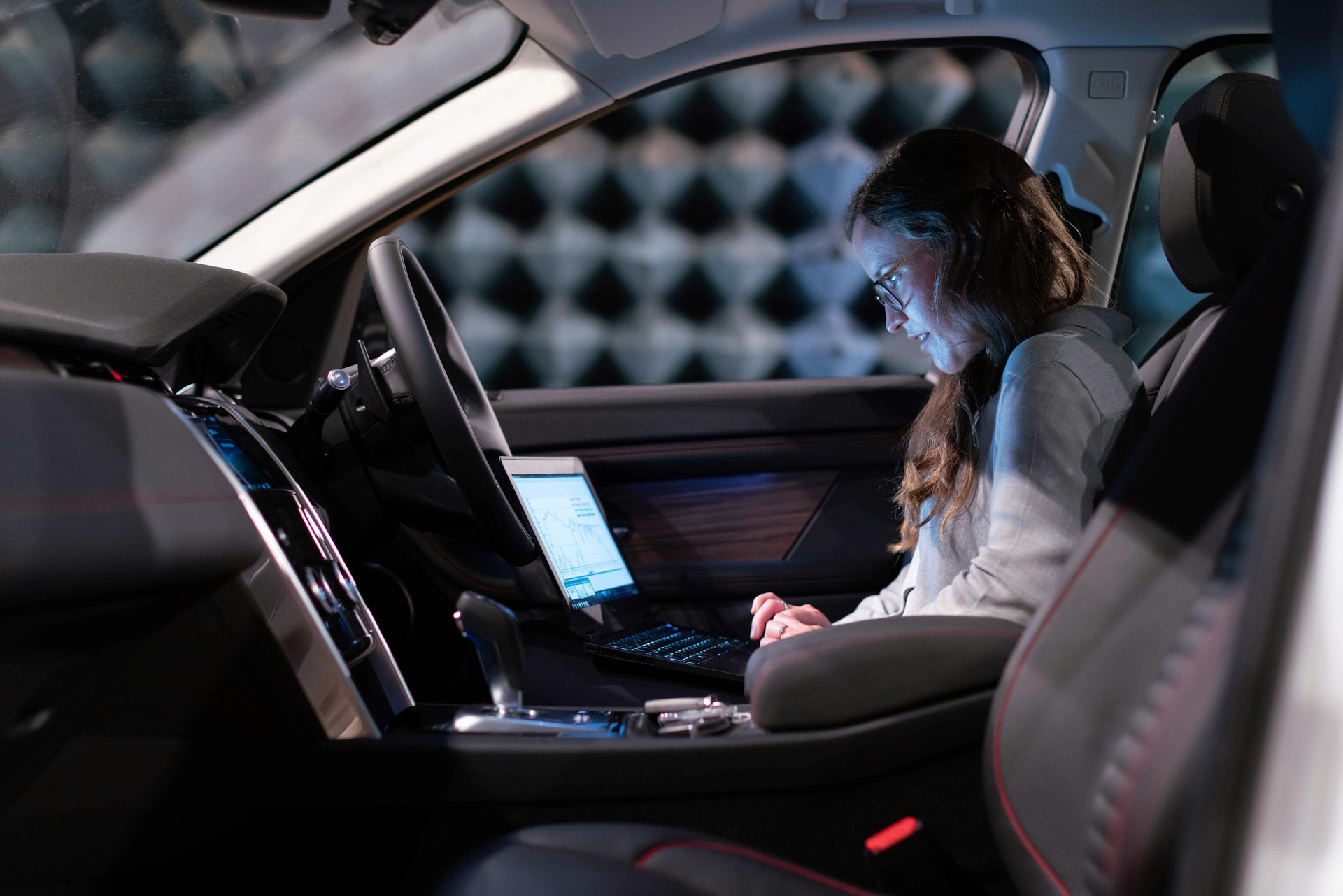Picture of a lady on a laptop, browsing a website, whilst in a self driving car